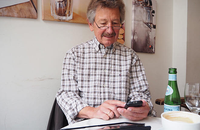 Uwe sitzt im Café und tippt auf sein Smartphone